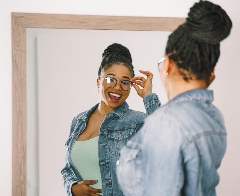 Image d'une femme souriante se regardant dans le miroir, symbolisant une image de soi positive